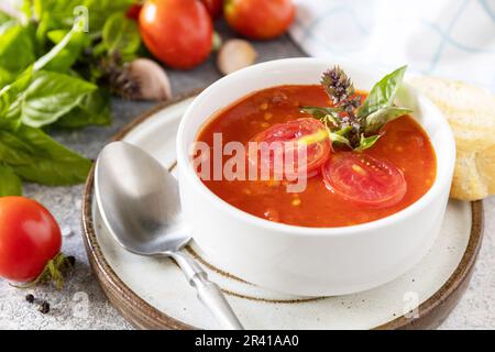 Vegetarische gesunde Ernährung. Vegane Suppenpüree Tomaten. Schüssel Tomatensuppe mit Basilikum und Croutons auf einem Steintisch. Stockfoto