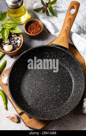 Leere Pfanne, Gemüse, Gewürze und Kräuter auf grauem Steinhintergrund. Hintergrund zum Kochen von Speisen mit Bratpfanne. Stockfoto