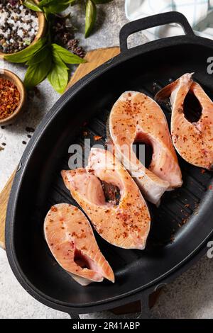 Frische Lachsfilets mit Gewürzen auf einer Grillpfanne. Fisch und Meeresfrüchte, kulinarischer Hintergrund. Stockfoto