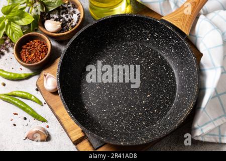 Leere Pfanne, Gemüse, Gewürze und Kräuter auf grauem Steinhintergrund. Hintergrund zum Kochen von Speisen mit Bratpfanne. Stockfoto
