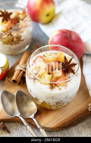 Gesundes Frühstücksgranola, gesunder Lebensstil. Hausgemachtes Dessert mit Joghurt, Müsli, Karamell-Äpfeln und Zimt auf einem Steinteller Stockfoto