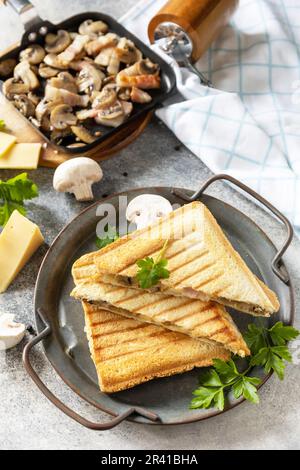 Köstliches Club-Sandwich, hausgemachter gegrillter Käse, Speck- und Pilzbrot zum Frühstück auf einer Steinplatte. Stockfoto