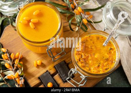 Frische reife Sanddornbeere mit Zucker und Sanddorngelee auf einem Steintisch. Hausgemachte, konservierte Beeren. Stockfoto