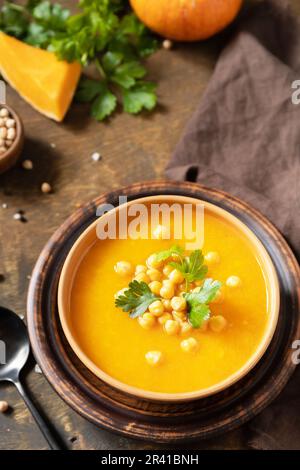 Comfort Food, Herbst und Winter gesundes Slow Food Konzept. Vegetarische Kürbis- und Kichererbsencremesuppe auf einem rustikalen Holztisch. Stockfoto