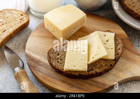 Konzept gesunder Speisen, Frühstück, Superfood. Frisches Vollkornbrot mit Käse und ein Glas Mandelmilch auf einem Steintisch. Stockfoto