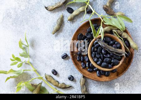 Bio-Lebensmittel. Der Begriff vegane oder diätetische Nahrung. Frische, reife schwarze Sojabohnen auf Steinhintergrund. Blick von oben. Stockfoto