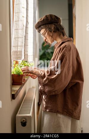 Hipstermädchen kümmert sich um Zimmerpflanzen, prüft, ob die Pflanze gesund ist. Pflanzenliebhaber. Stockfoto