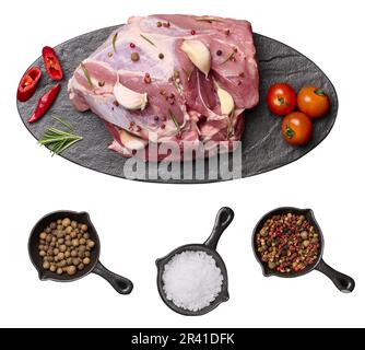 Ein Stück Schweineschinken auf einem schwarzen Brett und Gewürze, Pfeffer, Salz. Blick von oben Stockfoto