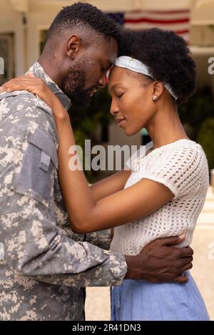 Liebenswerter afroamerikanischer Soldat, Mann und Frau, die Kopf an Kopf vor dem Haus stehen Stockfoto