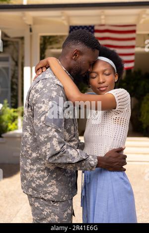 Seitenansicht eines afroamerikanischen Soldaten, der seine Frau umarmt, nachdem er von der Armee zurückgekehrt ist Stockfoto