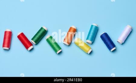 Mehrfarbige Nähfäden auf blauem Hintergrund, Draufsicht Stockfoto