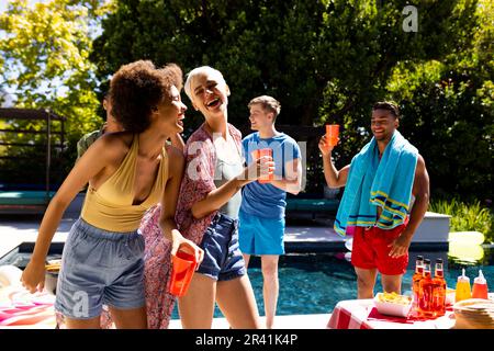 Fröhliche, vielfältige Gruppe von Freunden, die eine Poolparty veranstaltet und im Garten tanzt Stockfoto