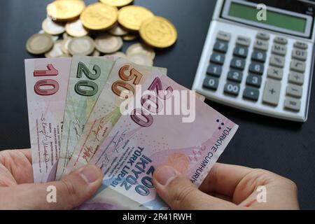 Ein Mann, der türkisches Geld mit der Hand zählt. Türkische Lira-Banknoten. Die Papierwährung der Türkei.Calculator im Hintergrund. Für Steuern und Wandernachrichten. Stockfoto