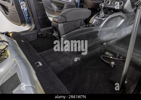 Rolle von Schallschutzmaterial zu Autoteilen. Die Installation der Schalldämmung des Fahrzeugs. Arbeiter klebt schallisolierendes Material auf die Innenseite des Stockfoto
