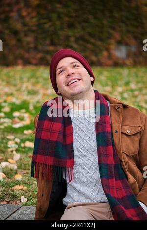 Lateinischer junger Mann mit Wollmütze und Schal, der im Winter lacht. Kaltes Wetter. Stockfoto