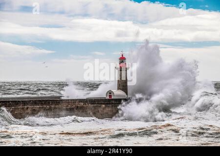 Wellen stürzen auf den alten Leuchtturm. Farolim de Felgueiras, Porto, Portugal. Stockfoto