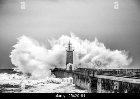 Wellen stürzen auf den Leuchtturm am Strand. Farolim de Felgueiras, Porto, Portugal Stockfoto