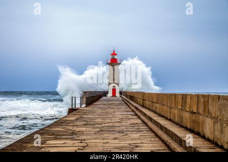 Wellen stürzen auf den Leuchtturm am Strand. Farolim de Felgueiras, Porto, Portugal Stockfoto