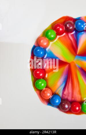 Knittert Süßigkeiten mit Zucker und Wasser verschmelzen zu farbenfrohem Regenbogenportal im vertikalen Hintergrund mit weißem Hintergrund dahinter Stockfoto