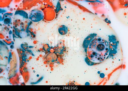 Horizontales abstraktes Hintergrundelement mit weißer Milch und blauer, orangefarbener und goldener Acrylfarbe, die mit Öl gefüllt ist und einen Marmoreffekt erzeugt Stockfoto
