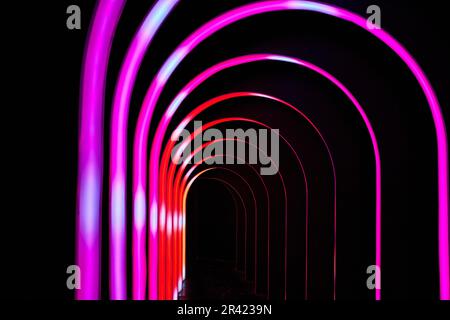 Bogengänge aus heißrosa und Hot Rod Red auf schwarzem Hintergrund Stockfoto