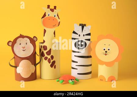 Spielzeugaffe, Giraffe, Löwe und Zebra aus Toilettenpapier auf gelbem Hintergrund. Handgemachte Kinderideen Stockfoto