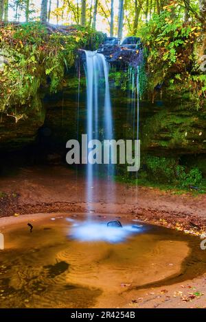 Blauer Wasserfall über Flechten, moosbedeckte Klippen in flaches Becken im Märchenwald Stockfoto
