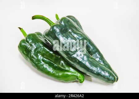Dunkelgrüne Poblano Peppers von oben mit weißem Hintergrund Stockfoto