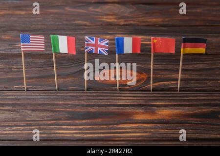 Viele kleine Papierflaggen verschiedener Länder auf einem Holztisch Stockfoto