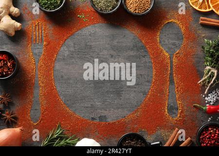 Flache Liegezusammensetzung mit verschiedenen Gewürzen, Bestecksilhouetten und Teller auf grauem Tisch. Platz für Text Stockfoto