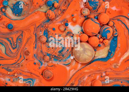 Horizontales Hintergrundmaterial galaktischer Malerei mit goldener runder Blase und Globen von wirbelndem Blau und Orange in abstrakter Malerei Stockfoto