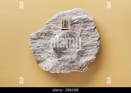 Parfümflaschen-Modell auf beigefarbenem Hintergrund. Kieselsteinpodium und trockene Hortensien. Natürliche Erdfarben Stockfoto