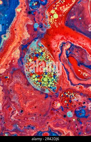 Abstrakte Embryonen von roten und gelben Acrylblasen, umgeben von einem Meer roter Farbe im Hintergrund-Asset Stockfoto