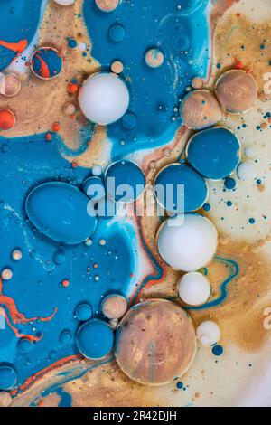 Abstraktes Acryl über Milch und Öl gießt, wodurch weiße Perlen, goldene Eier und blaue Blasen im vertikalen Hintergrund entstehen Stockfoto