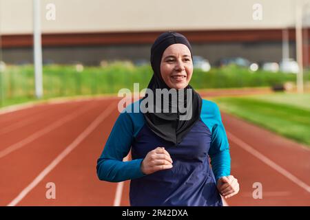 Eine muslimische Frau in einer Burka sportlich muslimische Kleidung, die auf einem Marathonkurs läuft und sich auf die nächsten Wettkämpfe vorbereitet Stockfoto