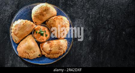 Zusammensetzung mit einem Teller aus im Ofen gebackenen Pierogi Stockfoto