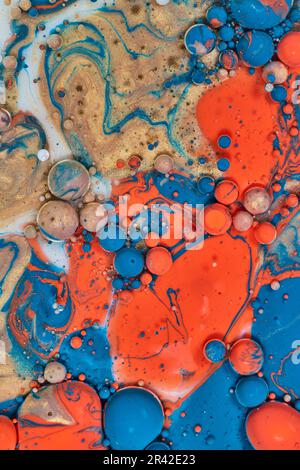 Abstrakte Farbspritzer mit orangefarbener, blauer, orangefarbener und weißer Milch in vertikaler Hintergrundmalerei mit farbigen Perlen Stockfoto