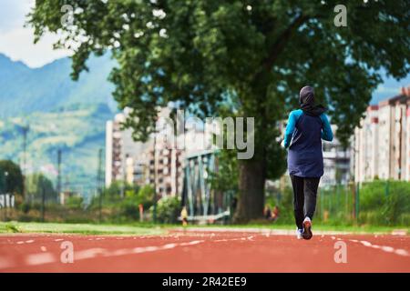 Eine muslimische Frau in einer Burka sportlich muslimische Kleidung, die auf einem Marathonkurs läuft und sich auf die nächsten Wettkämpfe vorbereitet Stockfoto