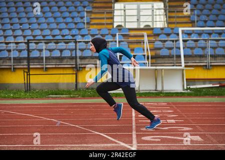 Eine muslimische Frau in einer Burka sportlich muslimische Kleidung, die auf einem Marathonkurs läuft und sich auf die nächsten Wettkämpfe vorbereitet Stockfoto