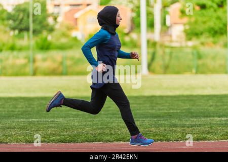 Eine muslimische Frau in einer Burka sportlich muslimische Kleidung, die auf einem Marathonkurs läuft und sich auf die nächsten Wettkämpfe vorbereitet Stockfoto