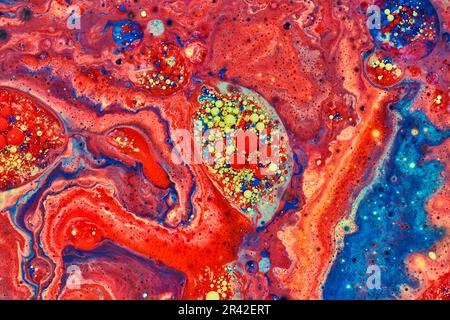 Horizontaler abstrakter Embryo von roten und gelben Acrylblasen, umgeben von einem Meer roter Farbe im Hintergrund-Asset Stockfoto
