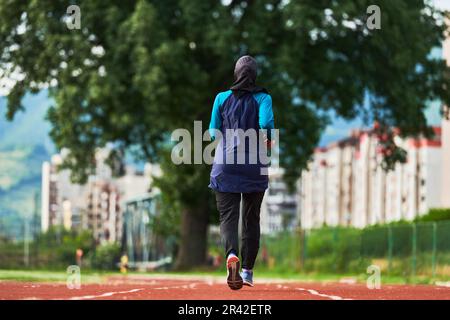 Eine muslimische Frau in einer Burka sportlich muslimische Kleidung, die auf einem Marathonkurs läuft und sich auf die nächsten Wettkämpfe vorbereitet Stockfoto