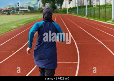 Eine muslimische Frau in einer Burka sportlich muslimische Kleidung, die auf einem Marathonkurs läuft und sich auf die nächsten Wettkämpfe vorbereitet Stockfoto