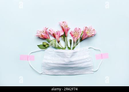 Danke Helden Doktor und Schwestern Konzept mit medizinischer Maske und rosa Blumen auf blauem Hintergrund Stockfoto