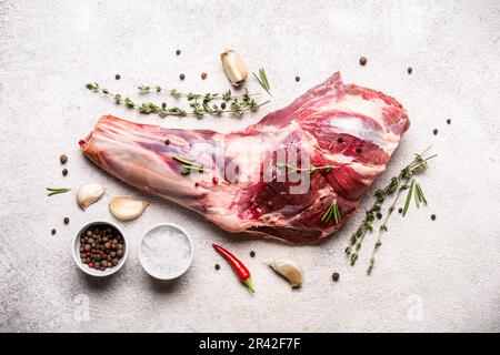 Rohes frisches Lammfleisch mit Schaft und Gewürzen auf grauem Betonhintergrund Stockfoto