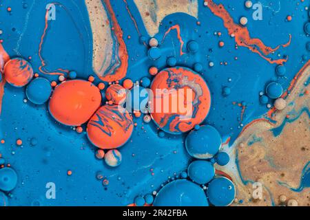 Abstraktes Meer aus blauer Acrylfarbe mit ostereierkugeln in Orange und Blau in Goldklumpen in horizontalem Hintergrund Stockfoto