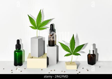 Kosmetische Mittel mit CBD-Öl und Hanfextrakt. Glasflaschen und Hanfblätter auf abstrakten geometrischen Podien mit trendigen Schatten Stockfoto