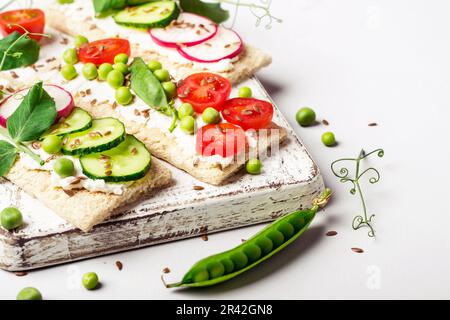 Gesunde Sandwiches mit Weichkäse und rohem Gemüse auf knusprigem Brot Stockfoto