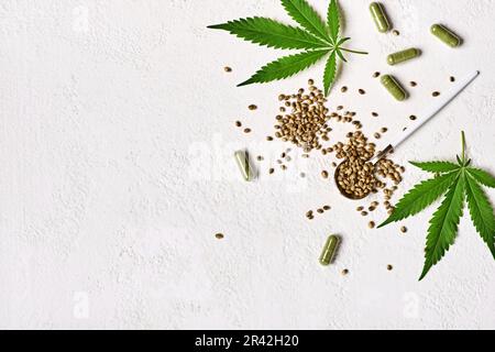 Kapseln für Cannabisarzneimittel, grüne Hanfblätter und Samen auf weißem Hintergrund. Anästhesie und sedative Wirkung Cannabiskonzept Stockfoto
