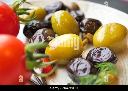 Sammlung schwarzer und grüner Oliven mit Blättern. Stockfoto